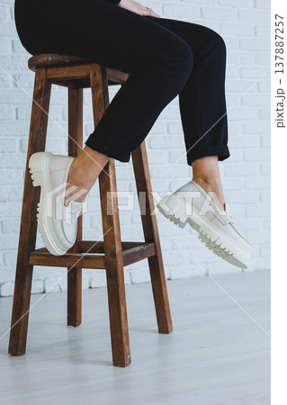 Legs of a young beautiful woman in black trousers and modern stylish white leather loafers. New collection of women's shoes spring-summer 2022 Legs of a young beautiful woman in black trousers and modern stylish white leather loafers. New collection of women's shoes spring-summer 2022 137887257