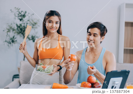 A happy couple prepares fresh vegetables, laughing and enjoying cooking a healthy meal together. A happy couple prepares fresh vegetables, laughing and enjoying cooking a healthy meal together. 137887304