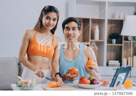 A happy couple prepares fresh vegetables, laughing and enjoying cooking a healthy meal together. A happy couple prepares fresh vegetables, laughing and enjoying cooking a healthy meal together. 137887306