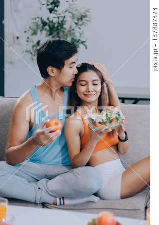 A happy couple prepares fresh vegetables, laughing and enjoying cooking a healthy meal together. 137887323