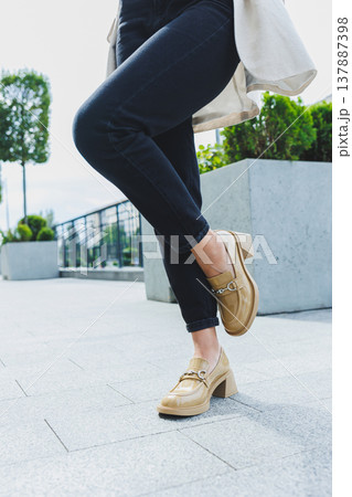 Female legs in black jeans and beige high heels. Beige leather shoes close-up 137887398