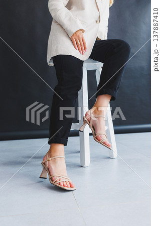 Women's legs close-up in summer brown flip-flops with heels. Summer collection of shoes for women made of genuine leather 137887410