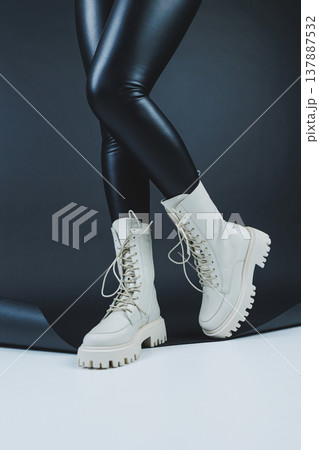 Close up of female legs in stylish fashion leather white lace up shoes. New seasonal collection of women's winter shoes. Close up of female legs in stylish fashion leather white lace up shoes. New seasonal collection of women's winter shoes. 137887532