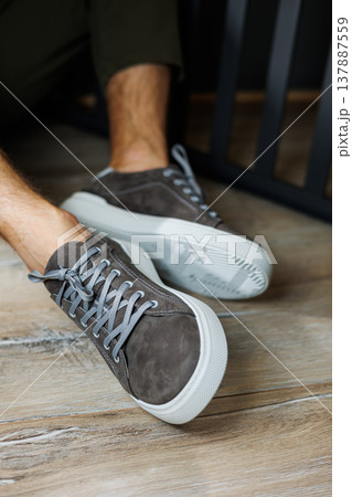Male legs in gray casual sneakers. Comfortable men's summer shoes. 137887559
