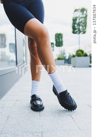 Female legs in leather shoes, white socks with and black moccasins, black shorts, fashion details Female legs in leather shoes, white socks with and black moccasins, black shorts, fashion details 137887634