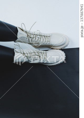 Close up of female legs in stylish fashion leather white lace up shoes. New seasonal collection of women's winter shoes. 137887641