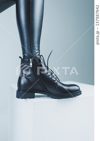 Female legs in leather black autumn boots. A fashion girl stands in a store and measures shoes. 137887642