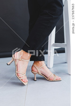 Women's legs close-up in summer brown flip-flops with heels. Summer collection of shoes for women made of genuine leather 137887663