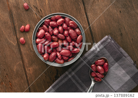 Red canned kidney beans served in a minimalist rustic style on a wooden table in a tin can top view Flat Lay. An open tin can filled to the brim with glossy red beans. Several beans are placed Red canned kidney beans served in a minimalist rustic style on a wooden table in a tin can top view Flat Lay. An open tin can filled to the brim with glossy red beans. Several beans are placed 137889162
