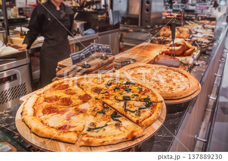 Freshly baked pizza, cut into segments - classic Pepperoni, as well as combined types of four seasons or assorted, where different fillings are assembled on the same base. a showcase of a typical Freshly baked pizza, cut into segments - classic Pepperoni, as well as combined types of four seasons or assorted, where different fillings are assembled on the same base. a showcase of a typical 137889230