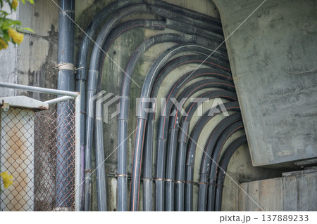 Laying of powerful power cables laid in HDPE protective pipes along a concrete structure concrete bridge or overpass engineering structure fragment. Safe transmission of electricity to high-voltage or 137889233