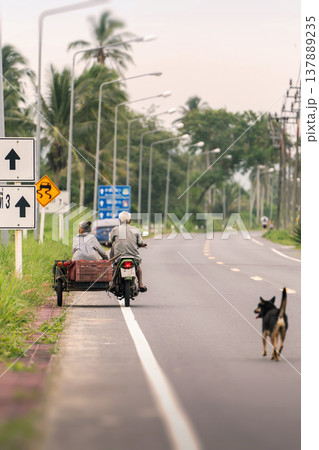 Authentic moments from the daily rural life of southern Thailand, which can be seen when traveling through Southeast Asia: an elderly couple rides a motorcycle with a sidecar attached for a passenger 137889235