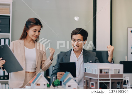 Real Estate Broker discussing with a customer model install solar roof house modern project in the office, real estate developer alternative energy, development business sustainable, zero energy, ESG. 137890504