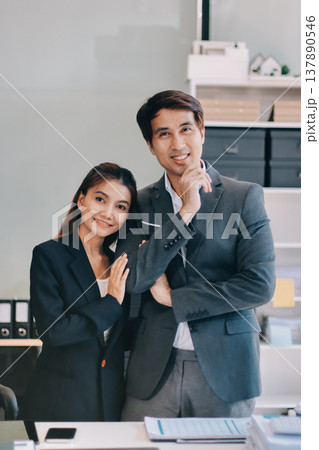 Portrait of a happy Asian business couple standing together. Young professional man and woman smiling in studio. Corporate teamwork concept Portrait of a happy Asian business couple standing together. Young professional man and woman smiling in studio. Corporate teamwork concept 137890546