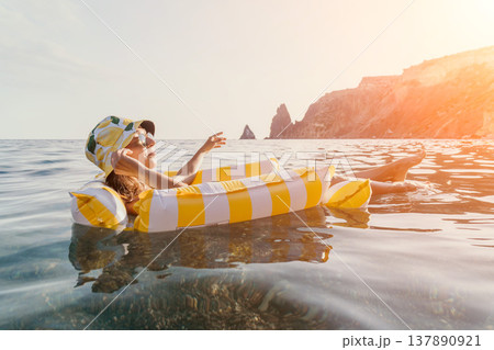 Woman Inflatable Raft Sea Relaxation - Woman floating on a yellow and white inflatable raft in the sea. Woman Inflatable Raft Sea Relaxation - Woman floating on a yellow and white inflatable raft in the sea. 137890921