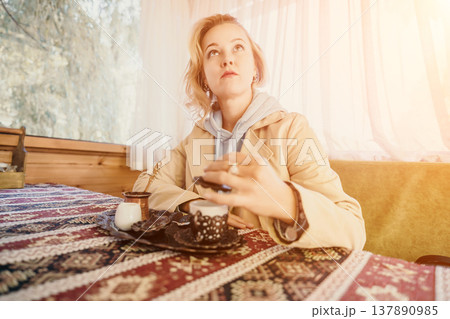 Woman, Coffee, Table: Young woman sits at a table drinking coffee in a cafe. Woman, Coffee, Table: Young woman sits at a table drinking coffee in a cafe. 137890985