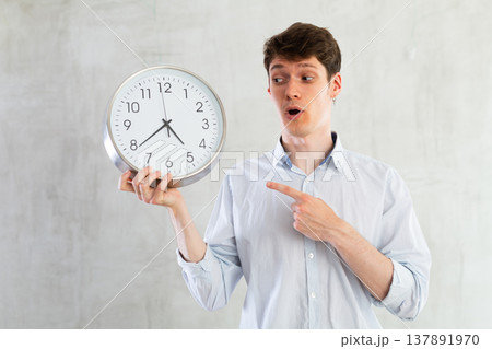 Man with a round big clock in his hands expresses various emotions 137891970