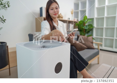 Air Purifier Control. User adjusting air purifier settings with smartphone. Air Purifier Control. User adjusting air purifier settings with smartphone. 137892351