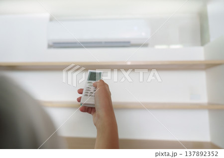 Air Conditioning Control. Hand using remote to adjust temperature settings. Air Conditioning Control. Hand using remote to adjust temperature settings. 137892352