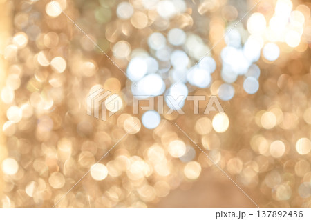 Golden bokeh lights with blurred circular highlights and warm tone creating an abstract light pattern suitable for luxury background use. 137892436