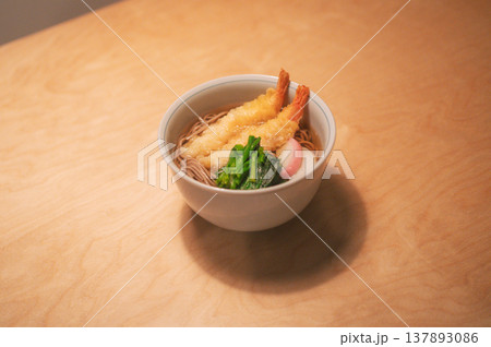 木目テーブルに置かれた海老天そばの温かい一杯と広い余白 137893086