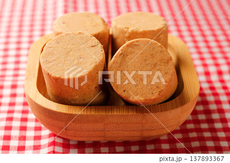 Pacoca, a traditional Brazilian sweet made of peanuts, served in a wooden bowl on a checkered tablecloth Pacoca, a traditional Brazilian sweet made of peanuts, served in a wooden bowl on a checkered tablecloth 137893367