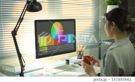 Graphic designer woman working on creative computer while using graphic tablet and holding coffee cup at desk in the office 137893661