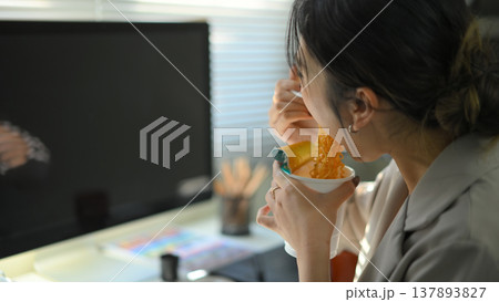 Closeup young woman eating instant noodles in office workplace Closeup young woman eating instant noodles in office workplace 137893827
