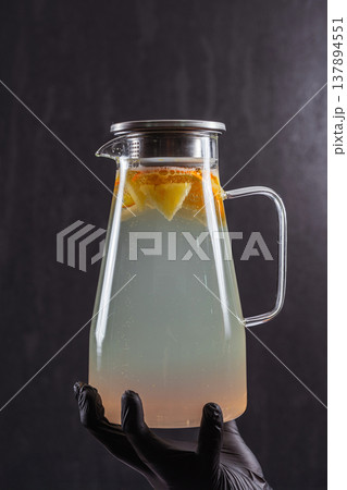 Clear Glass Pitcher Citrus Slices Held Blackgloved Hand, Moody Studio Lighting, Subtle Condensation 137894551
