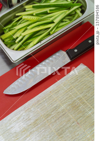 Sushi Prep With Knife And Mat, Cucumber Strips In Stainless Tray On Red Board, Bamboo Mat Ready Sushi Prep With Knife And Mat, Cucumber Strips In Stainless Tray On Red Board, Bamboo Mat Ready 137894586
