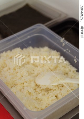 Plastic Container Filled With Sushi Rice And Scoop, Portion Ready For Service, Clear Lid Nearby, Plastic Container Filled With Sushi Rice And Scoop, Portion Ready For Service, Clear Lid Nearby, 137894631