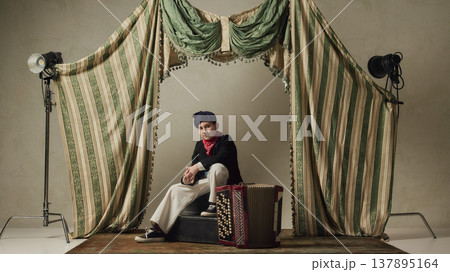 Teen boy sitting with accordion on stage resting after performance music portrait. 137895164