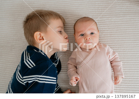 Older brother kissing newborn baby. Emotional moment of sibling love, tenderness and protection in family life. Older brother kissing newborn baby. Emotional moment of sibling love, tenderness and protection in family life. 137895167