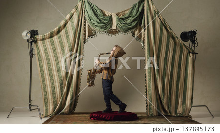 Little boy playing saxophone on small stage dramatic performance childhood music 137895173