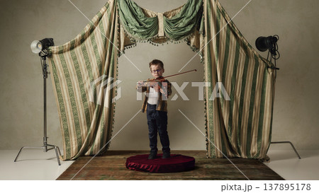 Little boy playing violin on studio stage with curtains classical scene. Little boy playing violin on studio stage with curtains classical scene. 137895178