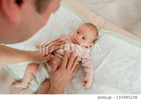 Father interacting and playing with newborn baby at home. Emotional bonding, early development and joyful parenting moment. 137895236