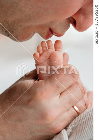 Father gently kissing tiny newborn baby feet. Emotional bonding moment expressing love, care, and connection in early days of parenthood. Soft lifestyle family scene. Father gently kissing tiny newborn baby feet. Emotional bonding moment expressing love, care, and connection in early days of parenthood. Soft lifestyle family scene. 137895250