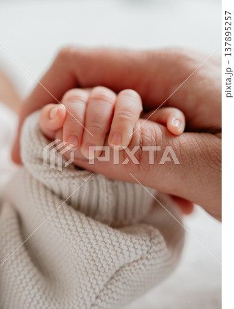 Tender moment of bonding between baby and parent. Minimalistic composition with soft textures and cozy clothing emphasizes intimacy and safety. Perfect for parenting and family themes. Tender moment of bonding between baby and parent. Minimalistic composition with soft textures and cozy clothing emphasizes intimacy and safety. Perfect for parenting and family themes. 137895257