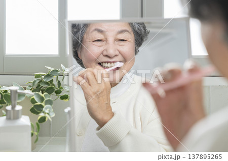 鏡を見ながら歯磨きをするシニア女性 137895265