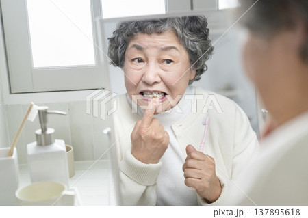 歯磨きの途中で歯茎を気にするシニア女性 歯磨きの途中で歯茎を気にするシニア女性 137895618