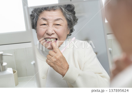 歯磨きの途中で歯茎を気にするシニア女性 137895624
