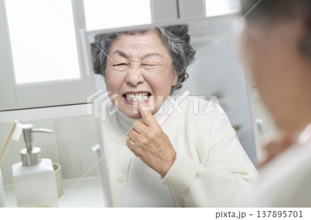 口腔内のトラブルイメージ　鏡を見て顔をしかめるシニア女性 137895701