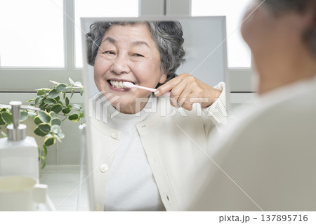 鏡を見ながら歯磨きをするシニア女性 137895716