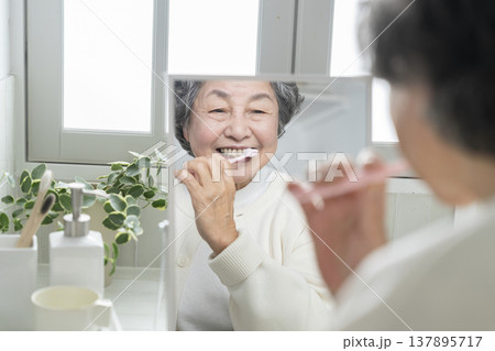 鏡を見ながら歯磨きをする80代の女性 137895717
