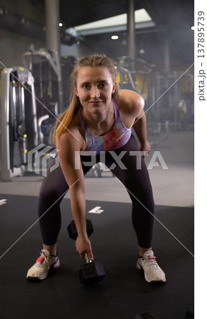 Fitness and health concept. A fit young woman works out in a modern gym. Athletic man doing exercise. Fitness and health concept. A fit young woman works out in a modern gym. Athletic man doing exercise. 137895739