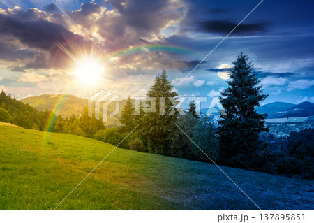 day meet night on mountain hay field. sun and moon over alpine countryside summer landscape with green valley behind the woods on the grassy slope at twilight. cloudy sky. epic highland background 137895851