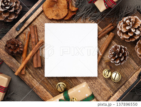 Square blank card on rustic wooden tray near Christmas decor top view. Holiday mockup Square blank card on rustic wooden tray near Christmas decor top view. Holiday mockup 137896550