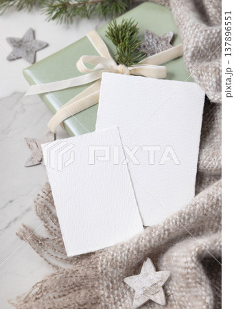 Christmas cards mockup on wrapped sage green gift box with ribbon bow and fir branch, top view 137896551