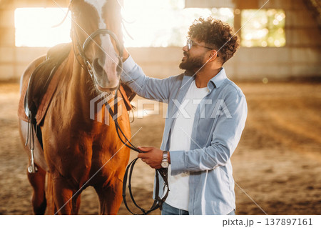 Stroking the animal with his hand. Man is with horse in the hangar Stroking the animal with his hand. Man is with horse in the hangar 137897161