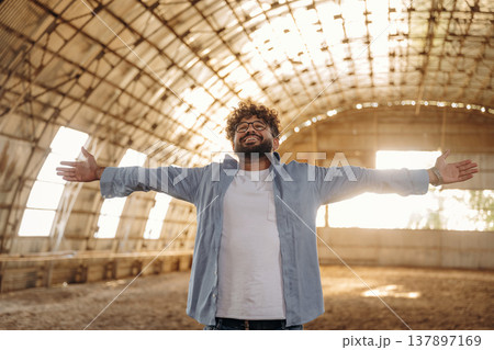 Hands to the sides, happy. Cheerful man in glasses is in hangar Hands to the sides, happy. Cheerful man in glasses is in hangar 137897169
